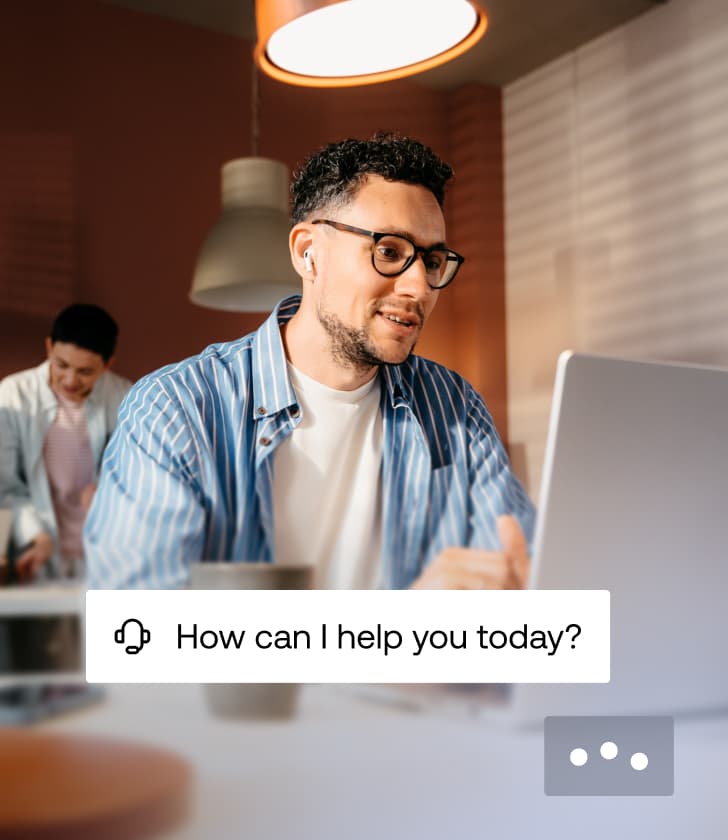 Support-Mitarbeiter mit Headset arbeitet an einem Laptop mit einem Overlay, das fragt: Wie kann ich Ihnen heute helfen?